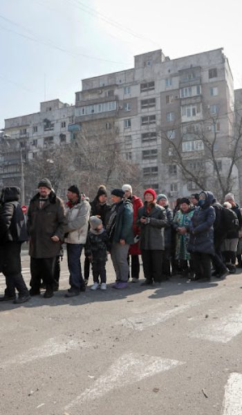A Russian soldier stands near residents queuing for food delivered during Ukraine-Russia conflict, in the besieged southern port of Mariupol, Ukraine, March 23 2022. Picture: ALEXANDER ERMOCHENKO/REUTERS